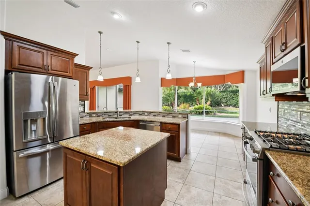 a kitchen with stainless steel appliances granite countertop a sink a stove and a refrigerator