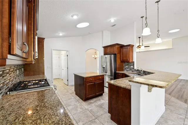 a kitchen with stainless steel appliances granite countertop a stove a sink dishwasher and a refrigerator with wooden floor