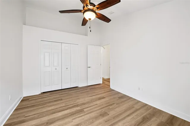 an empty room with wooden floor closet and windows