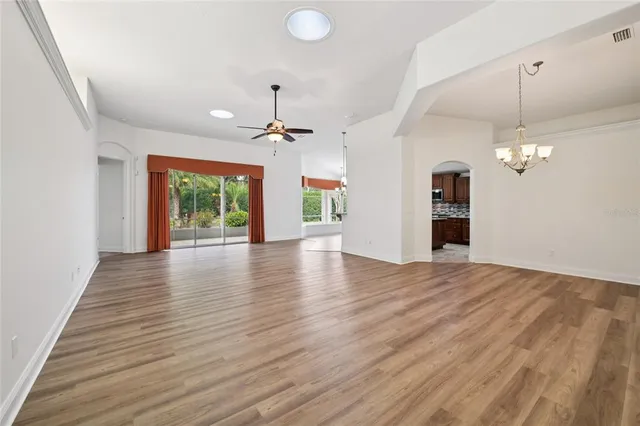 an empty room with wooden floor and chandelier