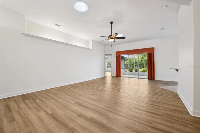 a view of an empty room with a window and wooden floor
