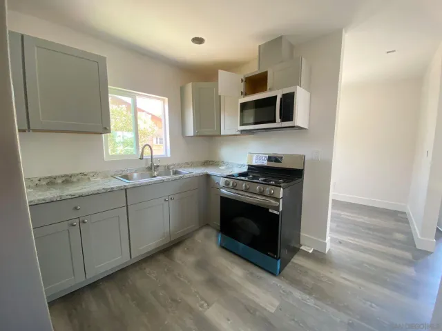 a kitchen with stainless steel appliances granite countertop a stove a sink and a microwave