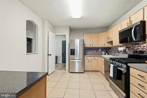 a kitchen with stainless steel appliances granite countertop a sink a stove a washer and dryer