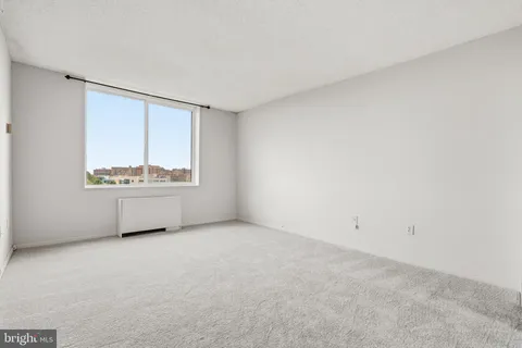 a bedroom with a bed large window and couch