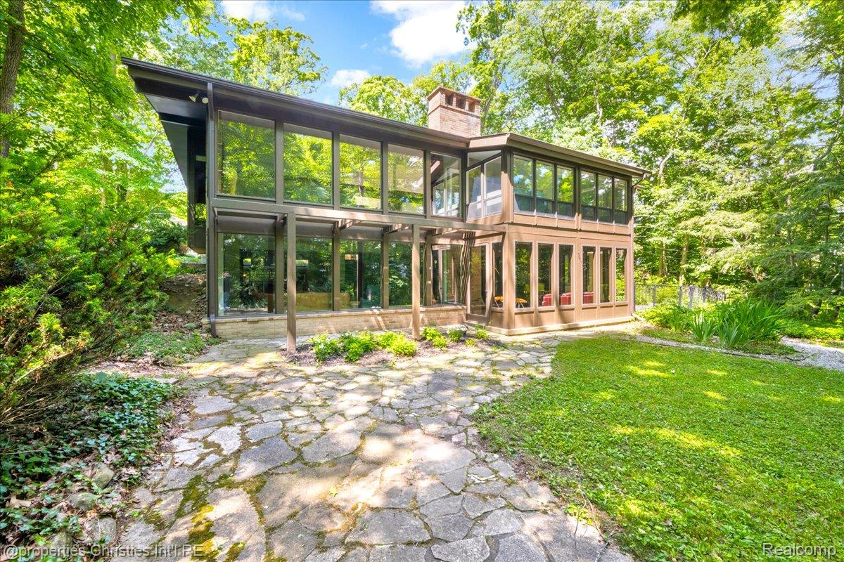 3939 Charing Cross Road Bloomfield Hills, MI 48304 - Photo 2 of 33 Contemporary architecture featuring extensive glazing, a stone chimney, and a stone patio