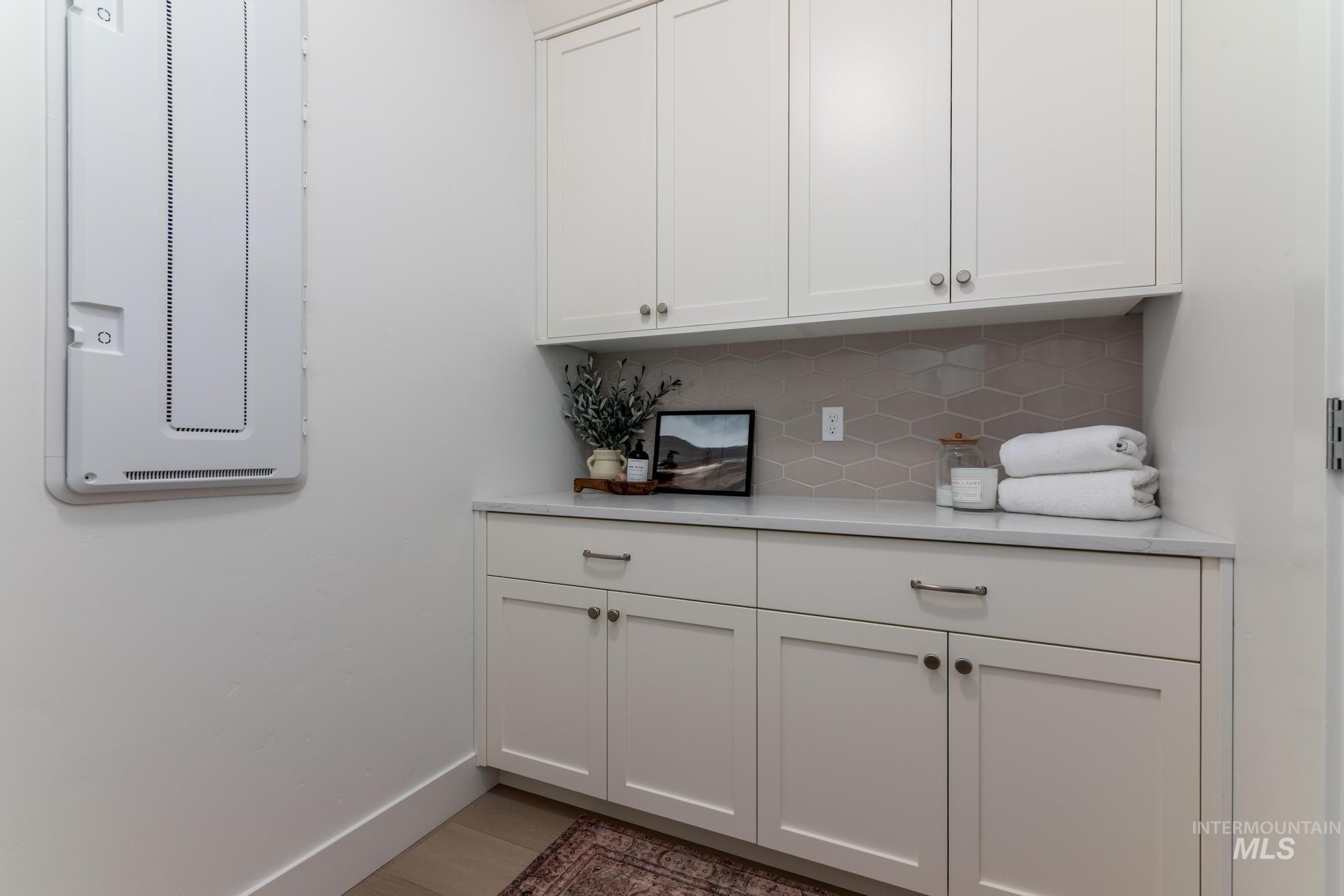 5431 North Ebony Way Meridian, ID 83646 - Photo 12 of 13 Bar area featuring white cabinets, backsplash, and light stone counters