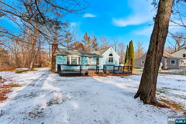 a view of a house with large tree and wooden fence