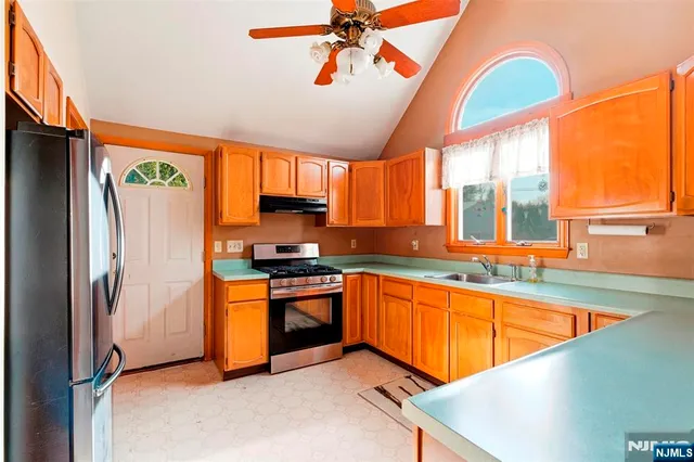 a kitchen with stainless steel appliances granite countertop a refrigerator a sink dishwasher a stove and a dining table with wooden floor