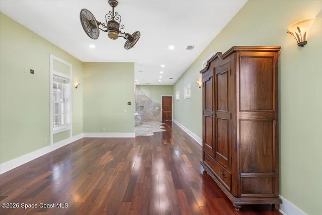 a view of empty room with wooden floor and fan
