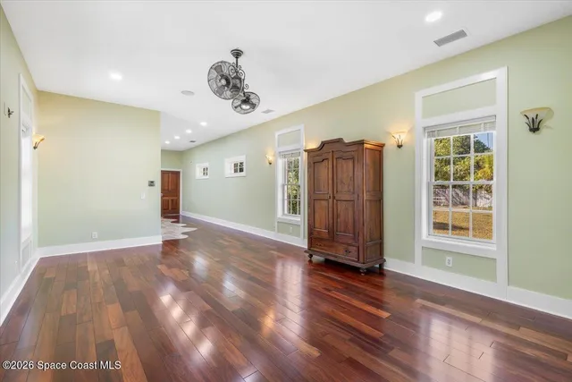 a view of an empty room with window and wooden floor