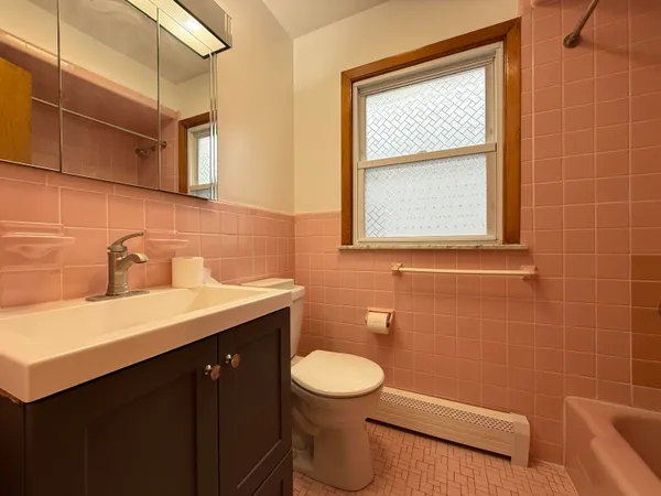 a bathroom with a sink mirror toilet and window