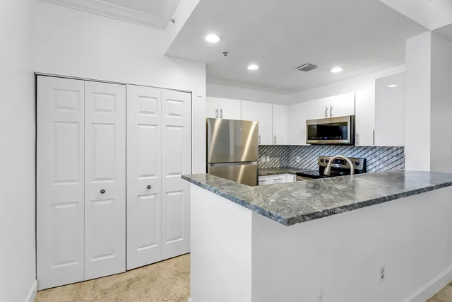 a kitchen with stainless steel appliances granite countertop a refrigerator a stove a sink and a granite counter tops