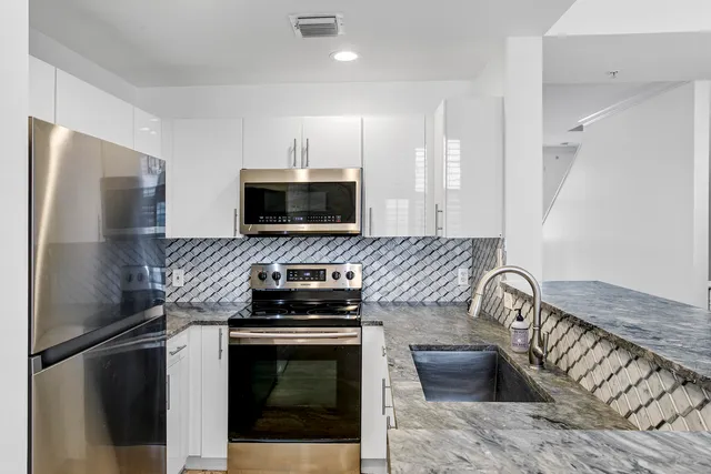 a kitchen with granite countertop a refrigerator and a stove top oven