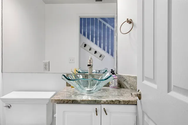 a view of kitchen island with granite countertop a sink a stove and white cabinets