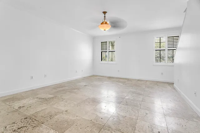 an empty room with windows and chandelier fan