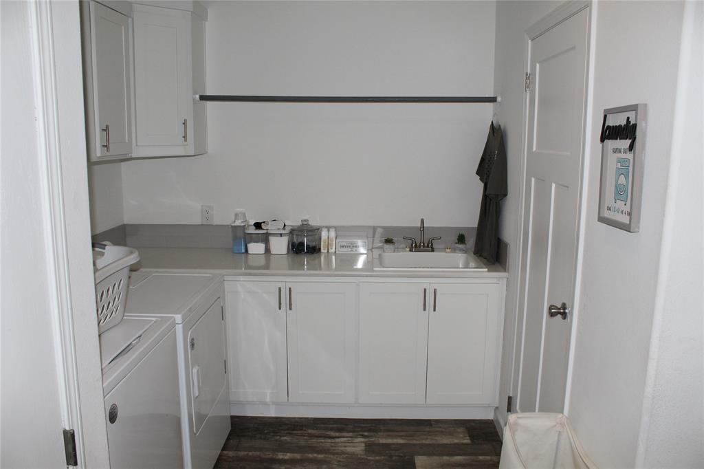 2077 A Shawver Road Perrin, TX 76486 - Photo 10 of 35 Functional laundry room featuring a utility sink, white shaker cabinetry, light-toned countertop, and wood-finish flooring