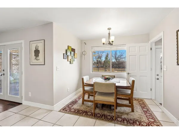 a dining room with wooden floor a chandelier a wooden table and chairs