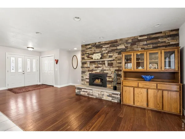 a living room with stainless steel appliances wooden floor and a fireplace