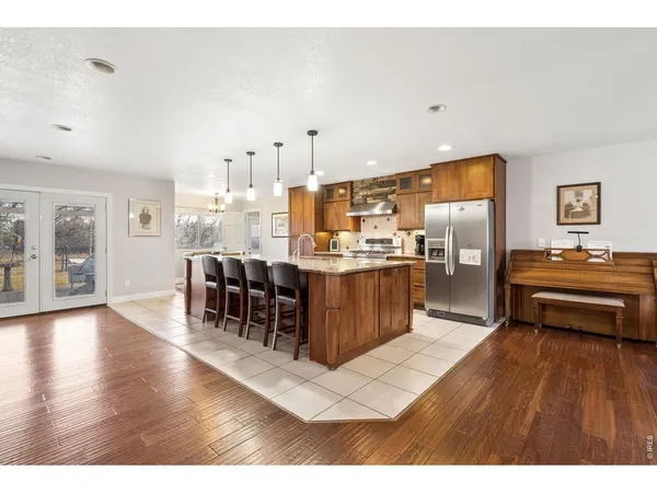 a kitchen with stainless steel appliances kitchen island granite countertop a refrigerator a stove and a wooden cabinets