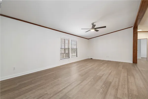 an empty room with wooden floor and ceiling fan