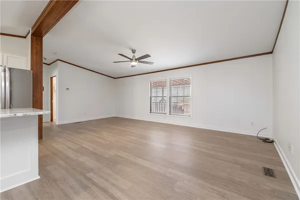 an empty room with wooden floor chandelier and windows