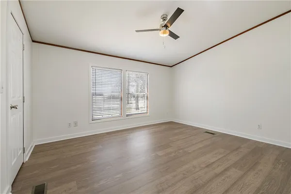 an empty room with wooden floor fan and windows