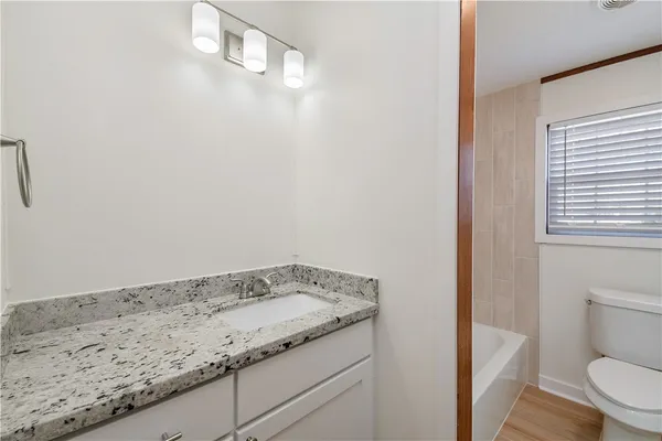 a bathroom with a granite countertop sink and toilet