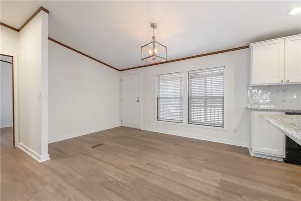 an empty room with wooden floor cabinet and windows