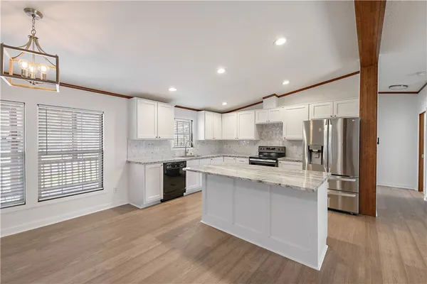 a kitchen with stainless steel appliances granite countertop a refrigerator a sink dishwasher a stove and a refrigerator with wooden floor