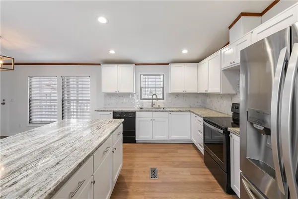 a large kitchen with granite countertop a large counter top space a sink stainless steel appliances and cabinets