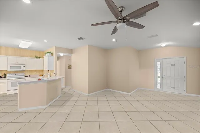 a large white kitchen with a stove a sink dishwasher and a refrigerator with white cabinets