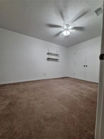 an empty room with a chandelier fan and windows