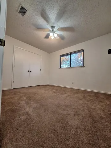an empty room with a ceiling fan and window