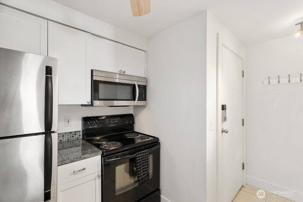 4831 Fauntleroy Way Southwest, Unit 206 Seattle, WA 98116 - Photo 4 of 21 a kitchen with white cabinets and stainless steel appliances