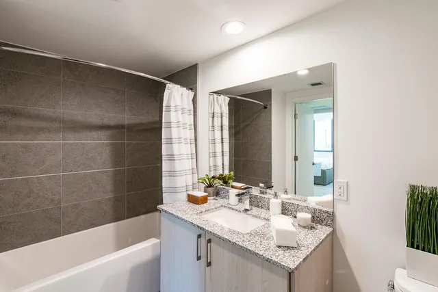 a bathroom with a granite countertop sink a mirror a bathtub and shower