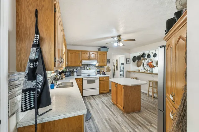 a kitchen with stainless steel appliances kitchen island granite countertop a stove a sink dishwasher and a dining table with wooden floor
