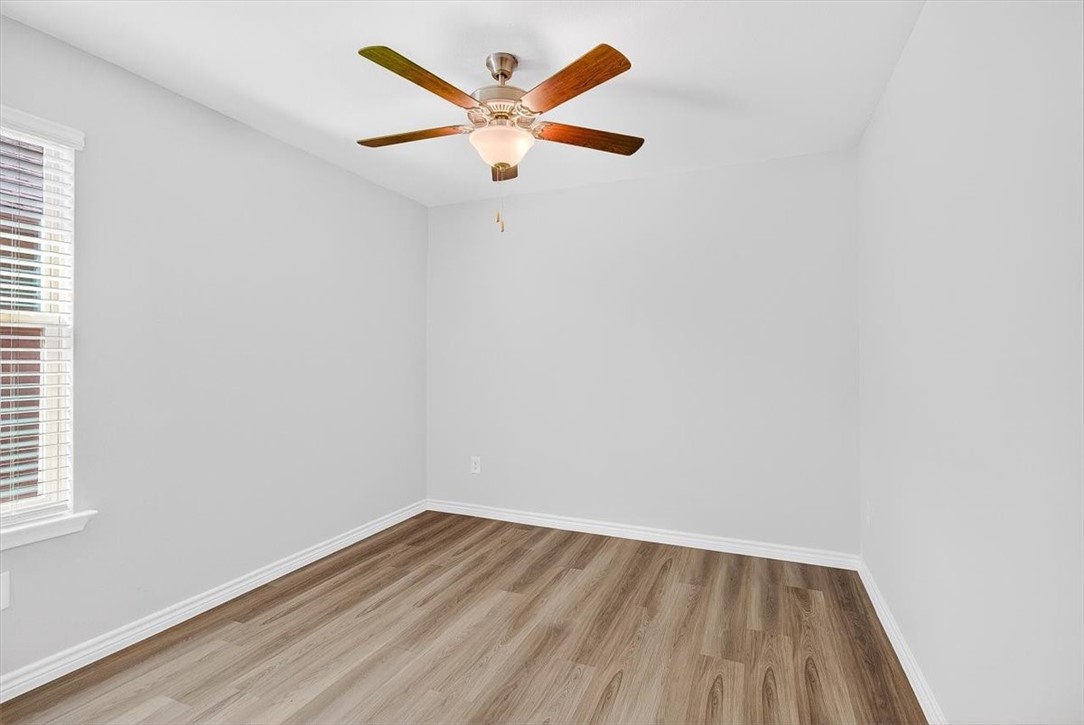 1626 Comfy Way Corpus Christi, TX 78418 - Photo 29 of 40 an empty room with wooden floor and a ceiling fan