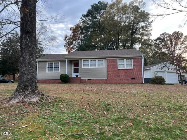 a view of a house with a yard and large tree