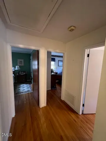 a view of a hallway with wooden floor and a living room