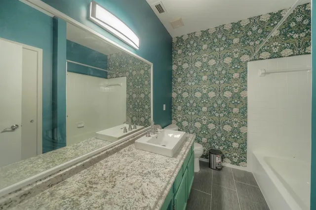 a bathroom with a granite countertop sink a toilet and shower