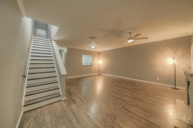 a view of an empty room with wooden floor and windows