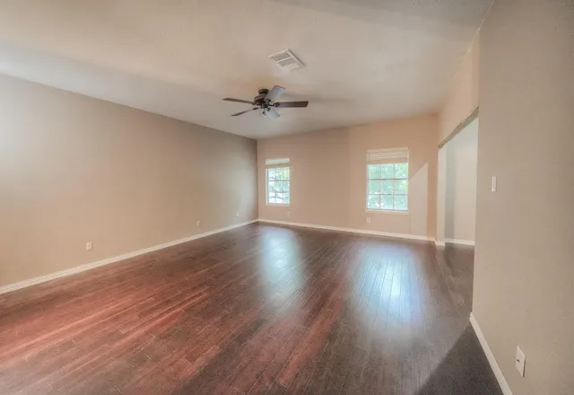an empty room with wooden floor and windows