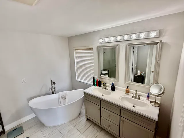a bathroom with a double vanity sink mirror and bathtub