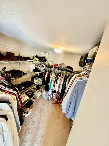 a view of walk in closet with clothes and shoes
