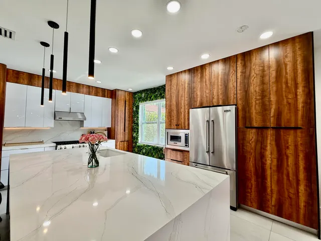 a kitchen with stainless steel appliances kitchen island granite countertop a refrigerator a stove and a sink with wooden floor