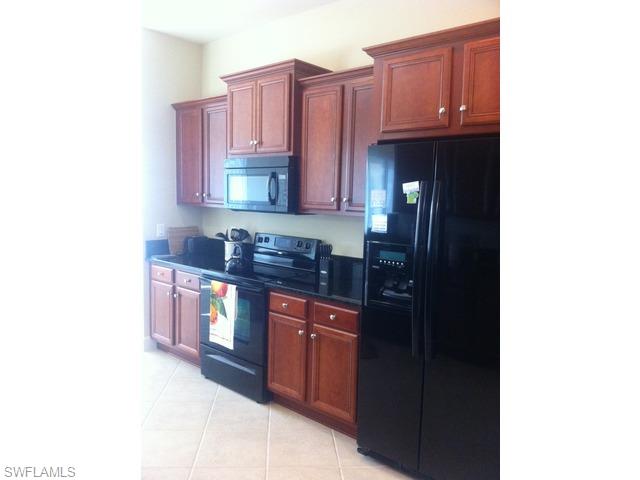 8248 Quaker Place Naples, FL 34104 - Photo 5 of 14 a kitchen with stainless steel appliances granite countertop a sink and cabinets
