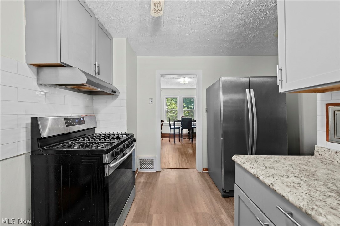 819 Keeney Street Akron, OH 44310 - Photo 21 of 24 Modern kitchen featuring light gray cabinetry, wood-finish flooring, white subway tile backsplash, stainless steel appliances, and light-toned countertops