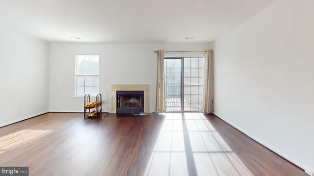 an empty room with wooden floor fireplace and windows