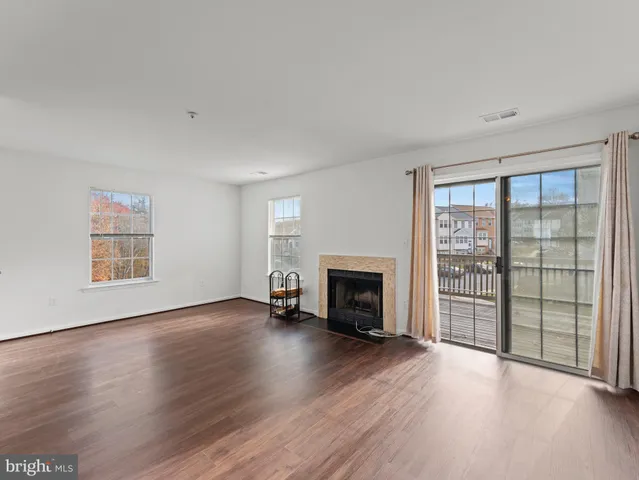an empty room with wooden floor fireplace and windows