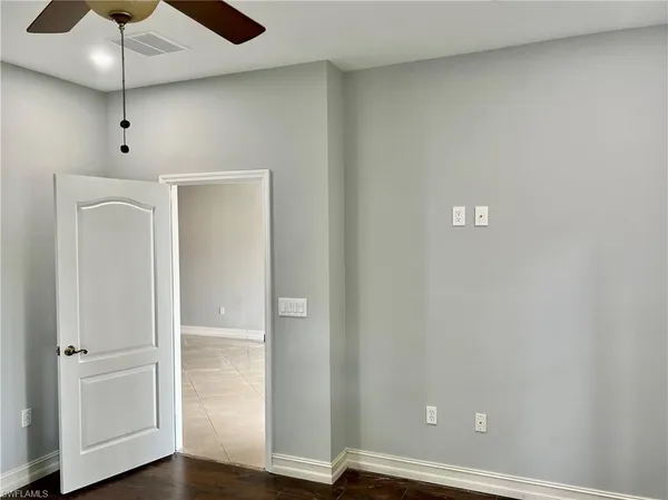 an empty room with wooden floor a ceiling fan and staircase